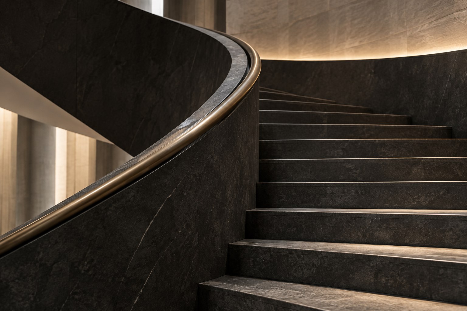 Sculptural charcoal staircase with a bronze handrail and soft natural light